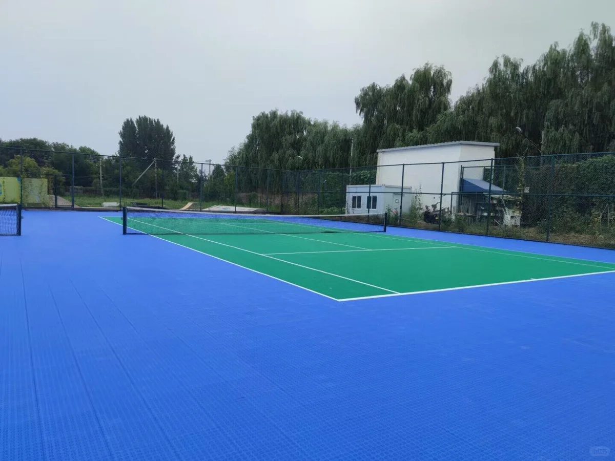 Outdoor court with a green playing area and blue surround